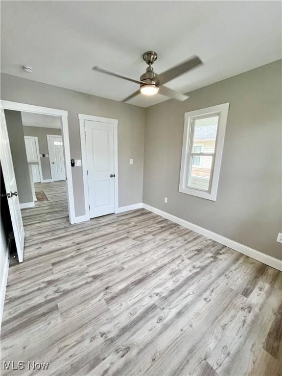 empty room with baseboards, a ceiling fan, and light wood-style flooring