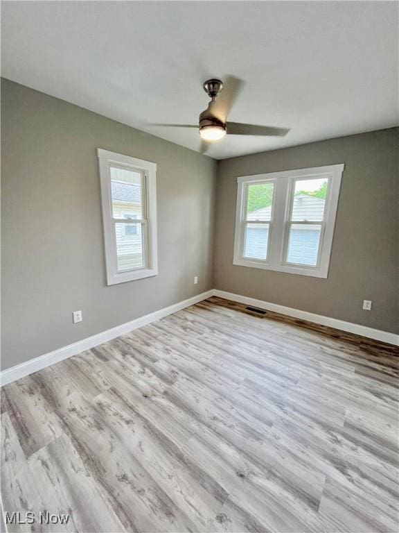 empty room featuring ceiling fan, baseboards, visible vents, and wood finished floors