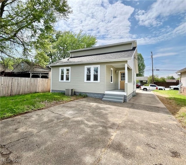 rear view of property with central AC unit, a shingled roof, fence, and concrete driveway