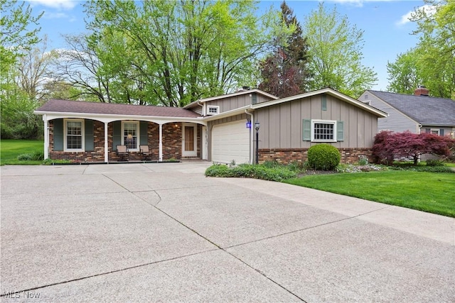 view of front of house featuring an attached garage, a front lawn, board and batten siding, concrete driveway, and covered porch