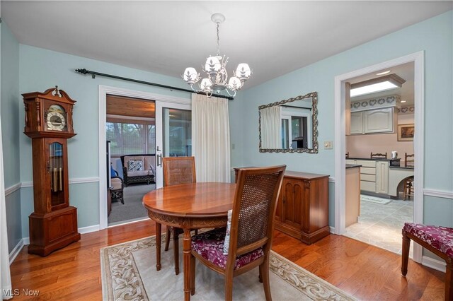 dining space with baseboards, light wood finished floors, and a chandelier
