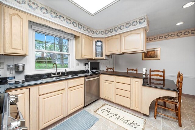 kitchen with dark countertops, a sink, recessed lighting, light tile patterned floors, and stainless steel dishwasher