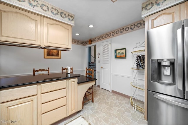 kitchen featuring light brown cabinetry, dark countertops, stainless steel fridge, recessed lighting, and baseboards
