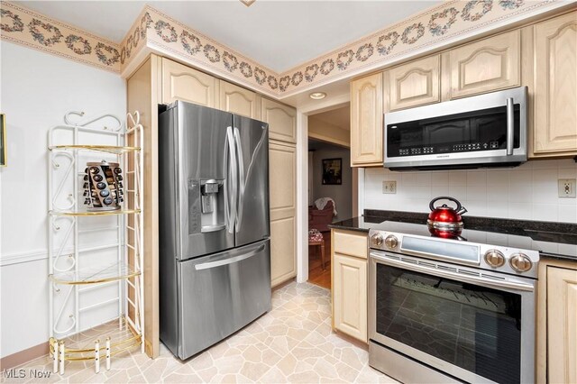 kitchen with backsplash, light brown cabinetry, dark countertops, and appliances with stainless steel finishes