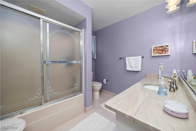 bathroom featuring tile patterned flooring, bath / shower combo with glass door, toilet, and vanity