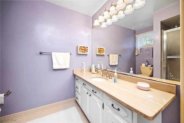 bathroom featuring tile patterned flooring, vanity, toilet, baseboards, and a shower stall