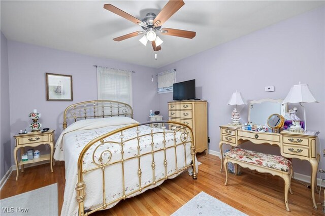 bedroom featuring baseboards, a ceiling fan, and light wood-style flooring