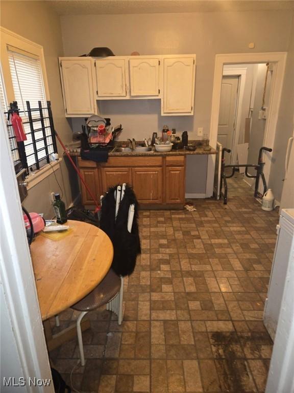 kitchen featuring white cabinetry, dark countertops, and brick patterned floor