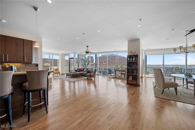 interior space with pendant lighting, light wood-style flooring, ceiling fan with notable chandelier, and dark brown cabinets