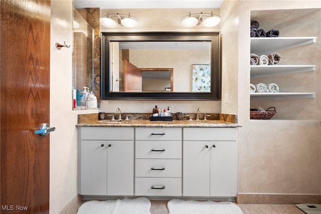 full bathroom featuring baseboards, a sink, and double vanity