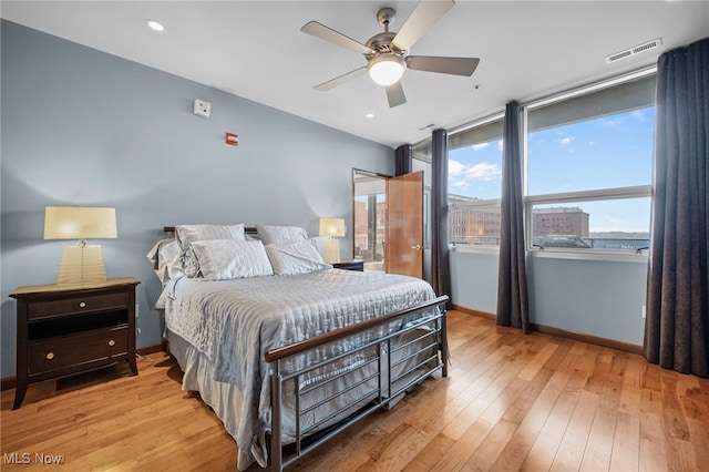 bedroom with wood-type flooring, baseboards, and multiple windows