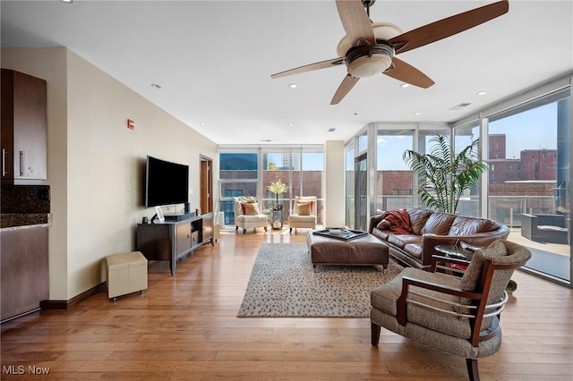 living area with light wood-style floors, floor to ceiling windows, ceiling fan, and visible vents
