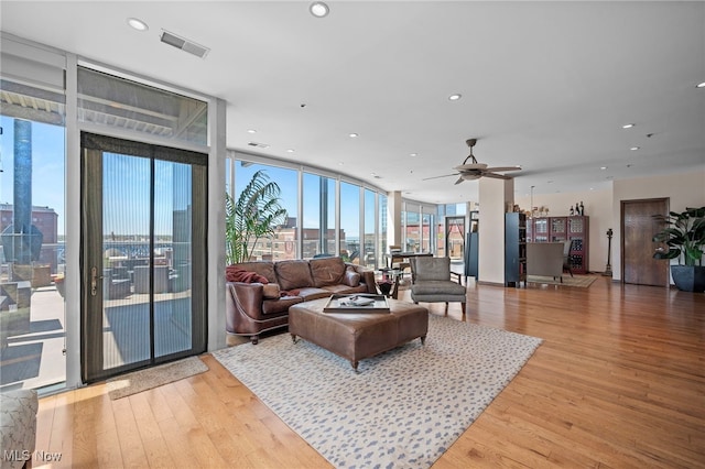 living area featuring ceiling fan, visible vents, expansive windows, light wood-style floors, and recessed lighting