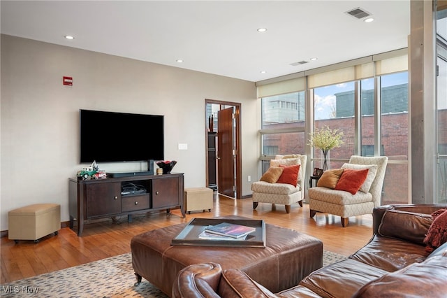 living area with floor to ceiling windows, recessed lighting, hardwood / wood-style floors, and visible vents