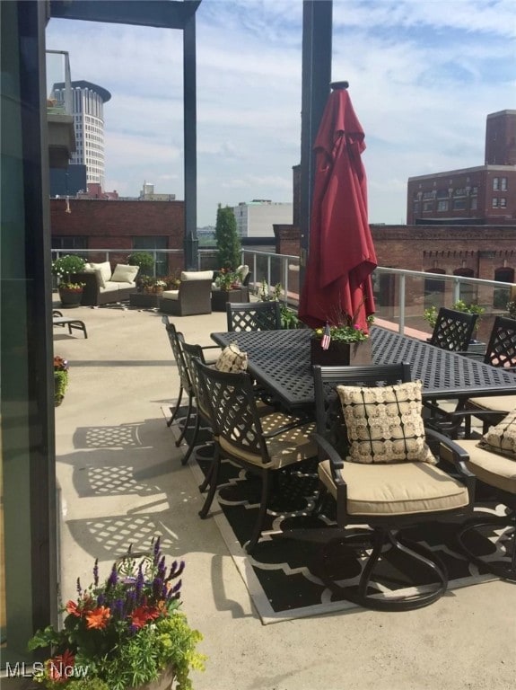 view of patio with a city view, a balcony, and outdoor dining space