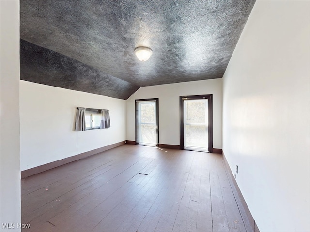 interior space with baseboards, vaulted ceiling, and hardwood / wood-style floors