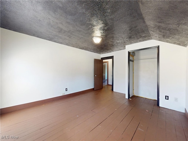 interior space with wood-type flooring, vaulted ceiling, and a closet