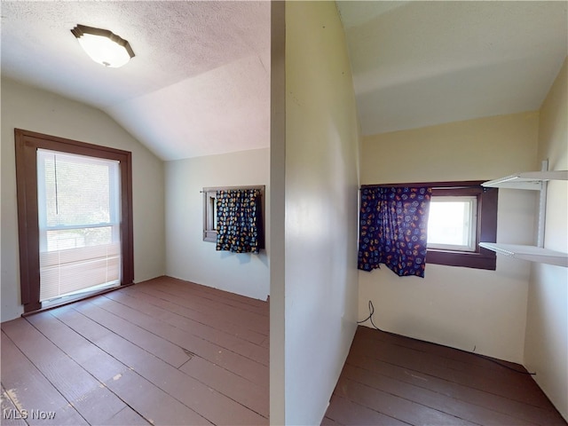 corridor with a textured ceiling, hardwood / wood-style floors, and lofted ceiling
