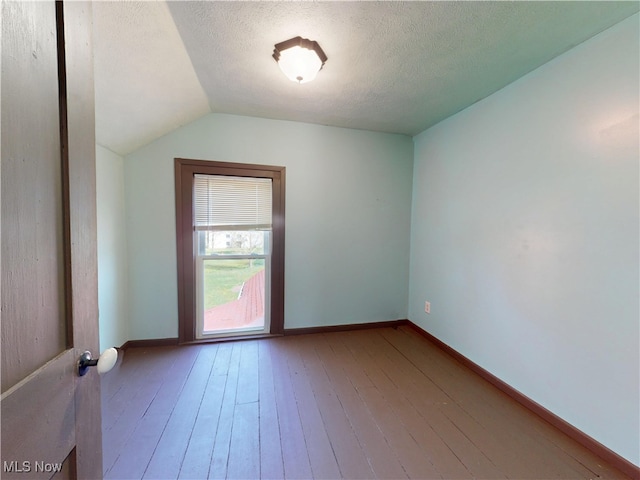 spare room with baseboards, a textured ceiling, lofted ceiling, and hardwood / wood-style floors
