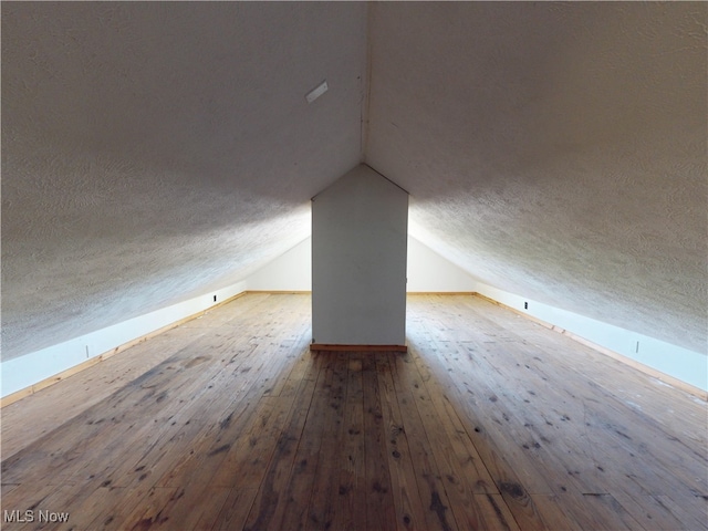 bonus room with a textured ceiling, vaulted ceiling, and hardwood / wood-style flooring