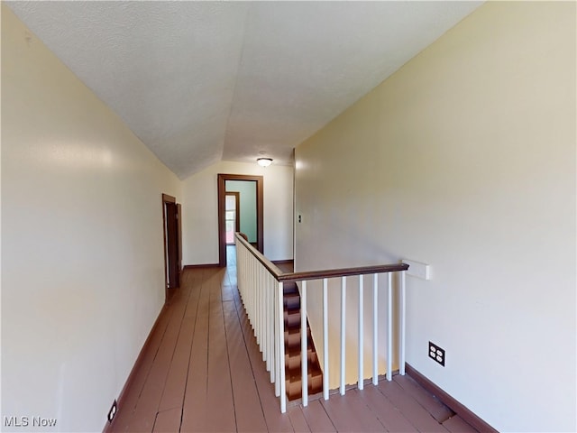 hall with wood-type flooring, baseboards, lofted ceiling, and an upstairs landing