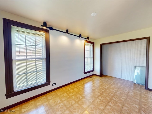 unfurnished bedroom with baseboards, multiple windows, a closet, and a barn door