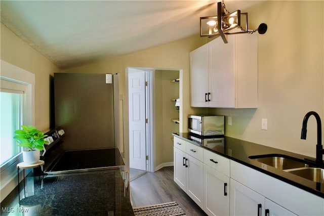 918 Pitkin Ave, Akron, OH 44310 - kitchen with white cabinets, a sink, stainless steel appliances, vaulted ceiling, and dark wood-style floors
