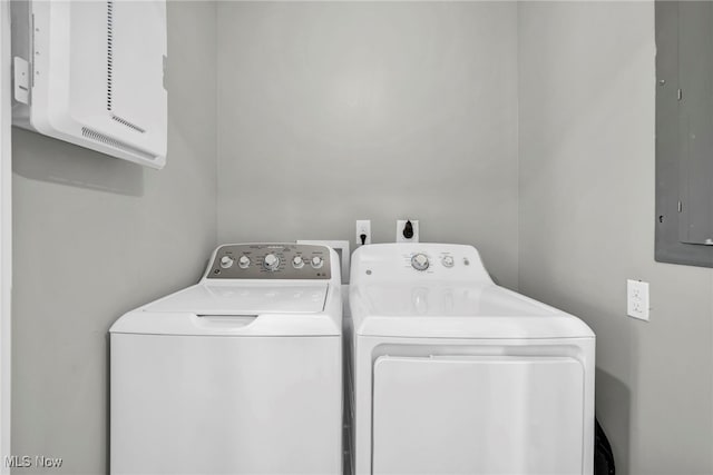 clothes washing area with washer and dryer, cabinet space, and electric panel