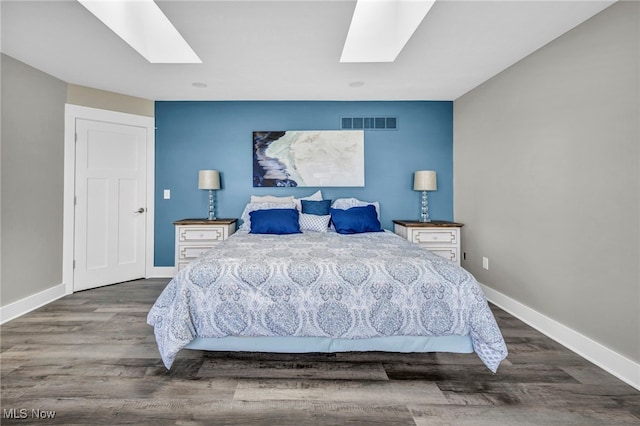 bedroom with visible vents, baseboards, wood finished floors, and a skylight