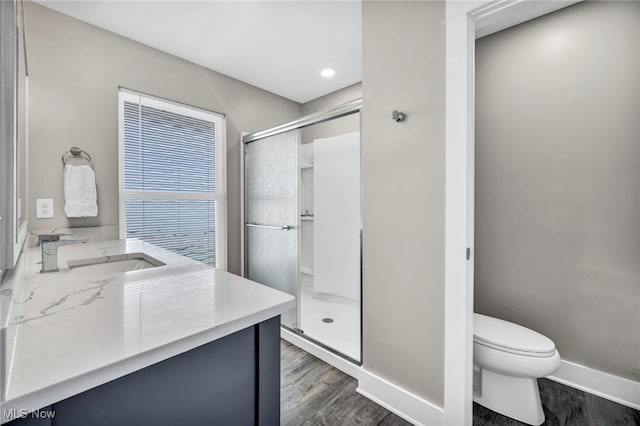 full bath featuring vanity, toilet, baseboards, a shower stall, and wood finished floors