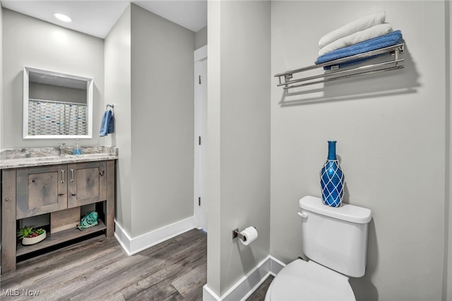 bathroom featuring baseboards, wood finished floors, toilet, and vanity