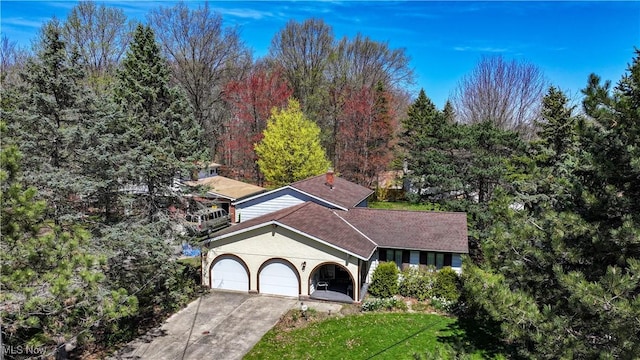 view of front of house featuring driveway, a front yard, a garage, a shingled roof, and stucco siding