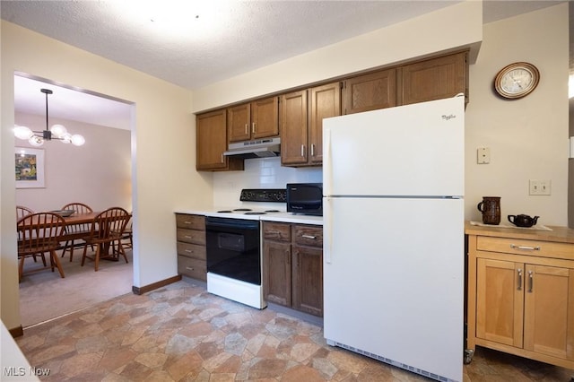 kitchen with freestanding refrigerator, stone finish flooring, under cabinet range hood, and range with electric stovetop