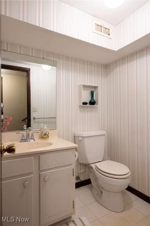 half bathroom with tile patterned flooring, vanity, toilet, wallpapered walls, and visible vents