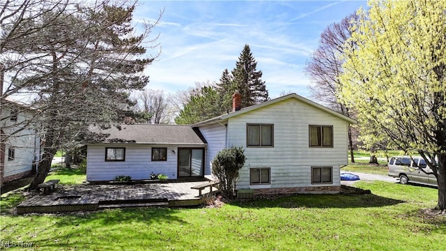 back of house featuring a lawn, a chimney, and a deck