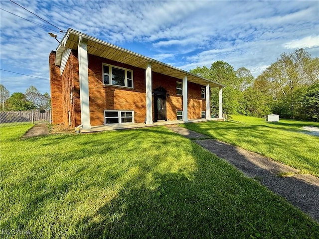 split foyer home featuring fence, a chimney, a front lawn, and brick siding