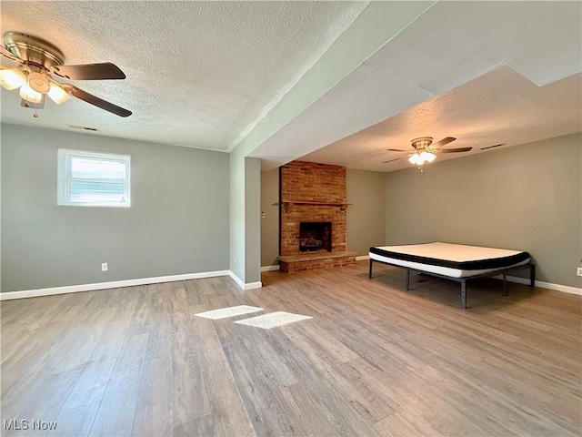 living room featuring baseboards, a ceiling fan, a textured ceiling, and wood finished floors