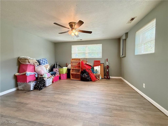 game room featuring a textured ceiling, a ceiling fan, wood finished floors, and visible vents