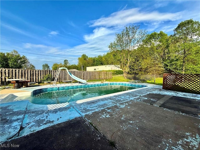 view of swimming pool featuring fence, a water slide, a patio area, and a fenced in pool