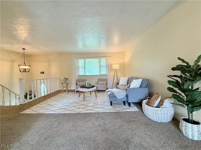 living area with a chandelier, carpet flooring, a textured ceiling, and an upstairs landing