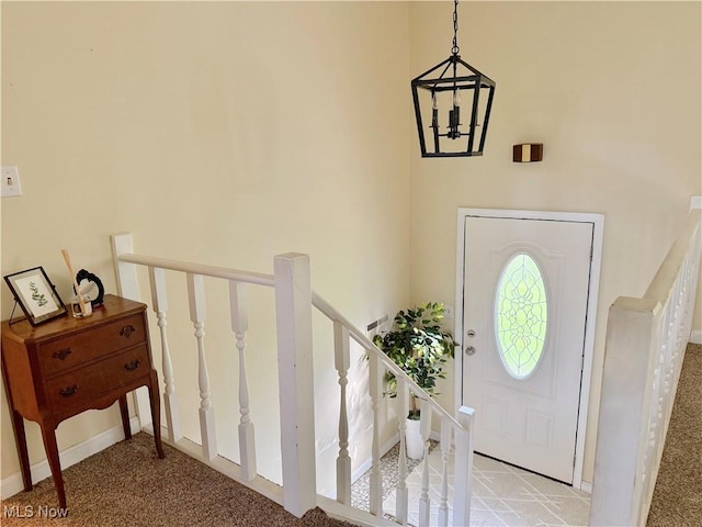 carpeted entryway with baseboards and a notable chandelier