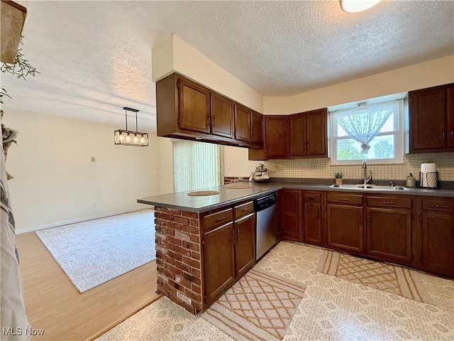 kitchen featuring a sink, dark countertops, stainless steel dishwasher, and a textured ceiling