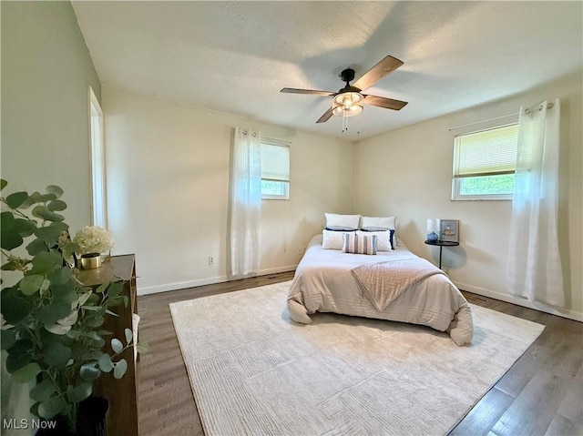 bedroom featuring baseboards, wood finished floors, and multiple windows