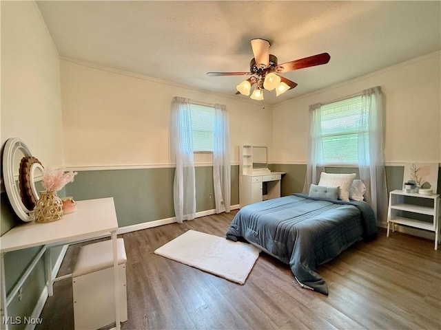 bedroom featuring crown molding, ceiling fan, multiple windows, and wood finished floors