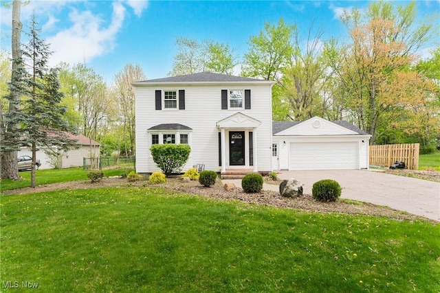 colonial-style house featuring a garage, a front lawn, fence, and concrete driveway