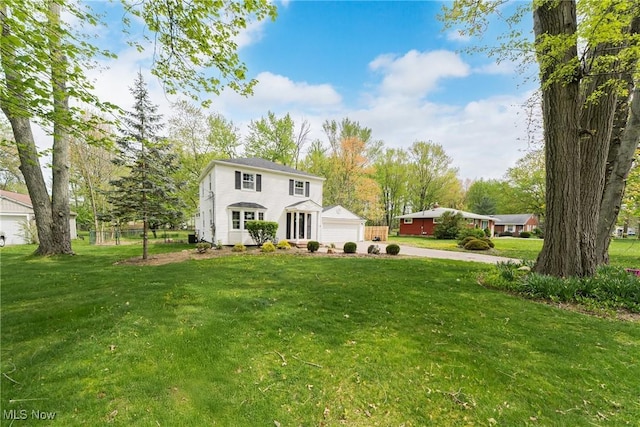 colonial-style house with a detached garage and a front lawn
