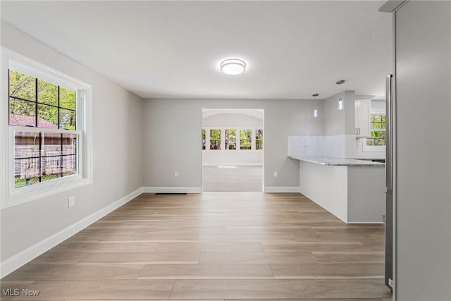 spare room featuring baseboards and light wood finished floors