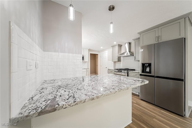 kitchen featuring backsplash, light stone counters, stainless steel appliances, wall chimney exhaust hood, and dark wood-type flooring