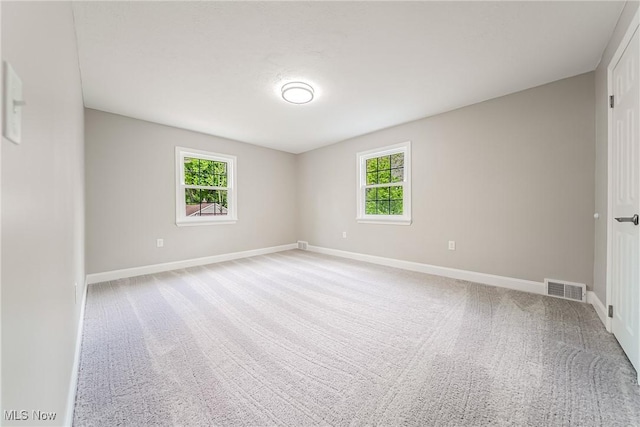 carpeted spare room featuring baseboards and visible vents