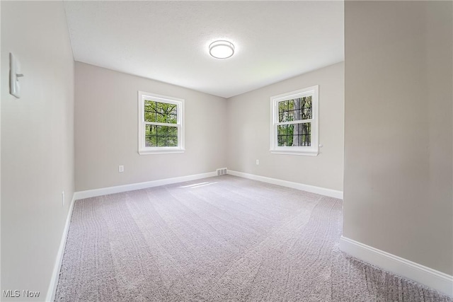 spare room featuring carpet floors, baseboards, and plenty of natural light